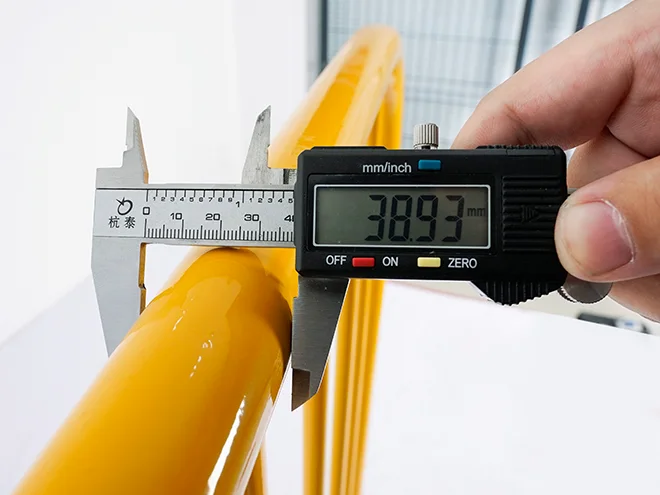 A QC worker is measuring the frame diameter of crowd control barrier.