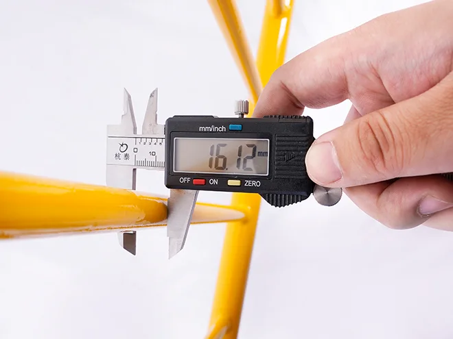 A QC worker is measuring the vertical tube diameter of crowd control barrier.