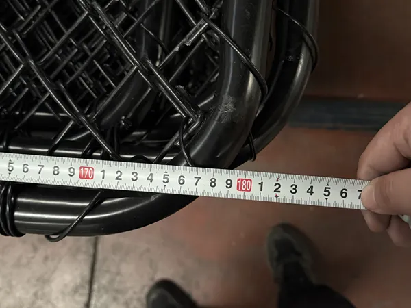 Worker is measuring customized chain link gates length with a tape measure