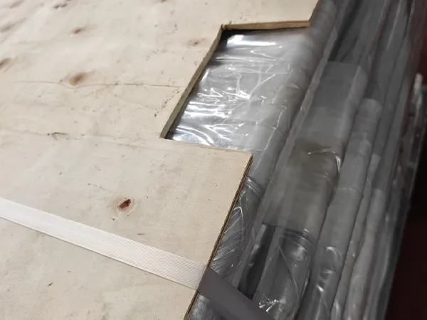 Customized chain link gates are wrapped in plastic film, covered with plywood, and secured with straps