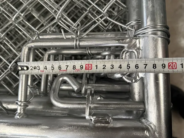 A worker is measuring the dimensions of the customized chain link gates galvanized metal fence structure with a tape measure.