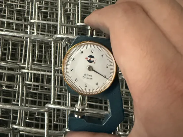 A worker is measuring the thickness of the customized chain link gates metal mesh with a thickness gauge.