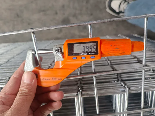 A QC worker is measuring the wire diameter of defensive barriers.