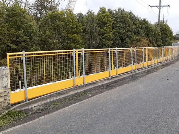 The yellow edge protection fences are installed at the roadside.