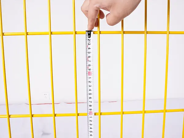 A QC worker is measuring the mesh size of edge protection fence.