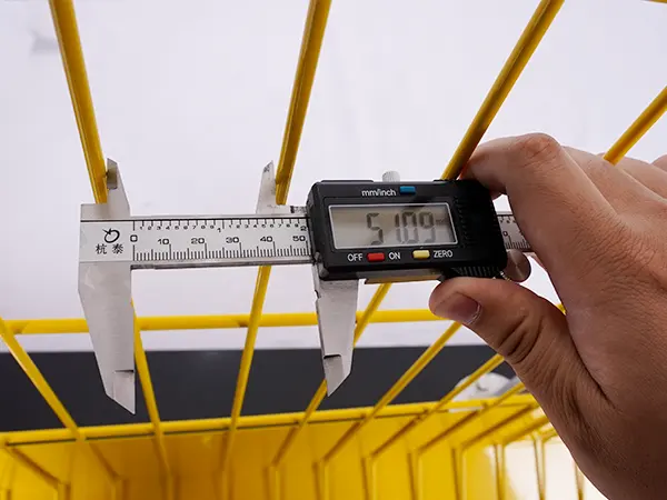 A QC worker is measuring the mesh size of edge protection fence.