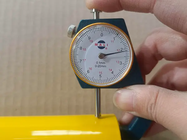 A QC worker is measuring the thickness of edge protection fence post.