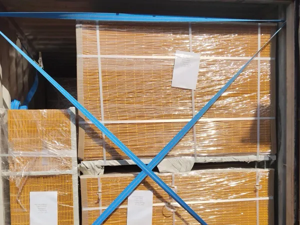Multiple sets of yellow edge protection fences wrapped in plastic film and secured with blue straps are stacked inside a container.