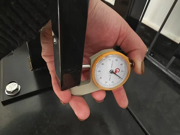 A QC worker is measuring the tubular thickness of sliding gate.