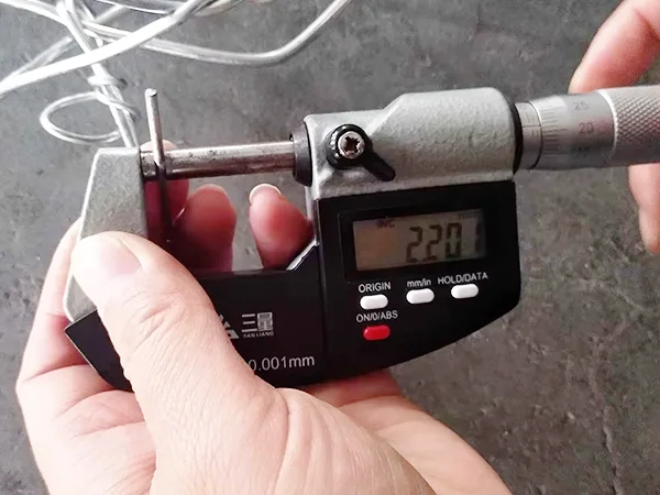 A QC worker is measuring the lacing wire diameter of woven gabion retaining wall.