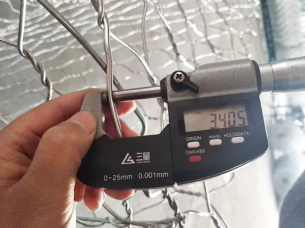 A QC worker is measuring the selvedge wire diameter of woven gabion retaining wall.