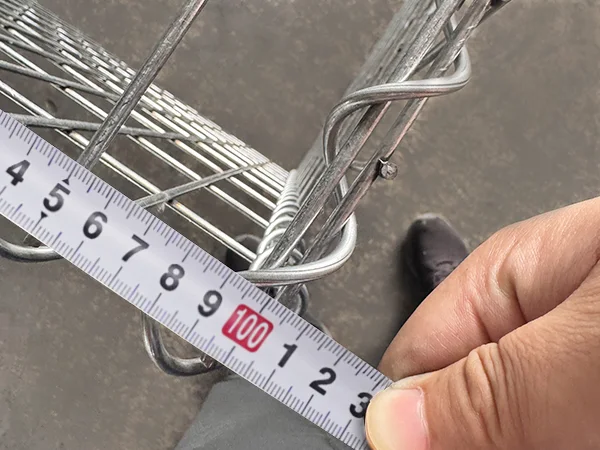 A QC worker is measuring the width of welded gabion retaining wall.