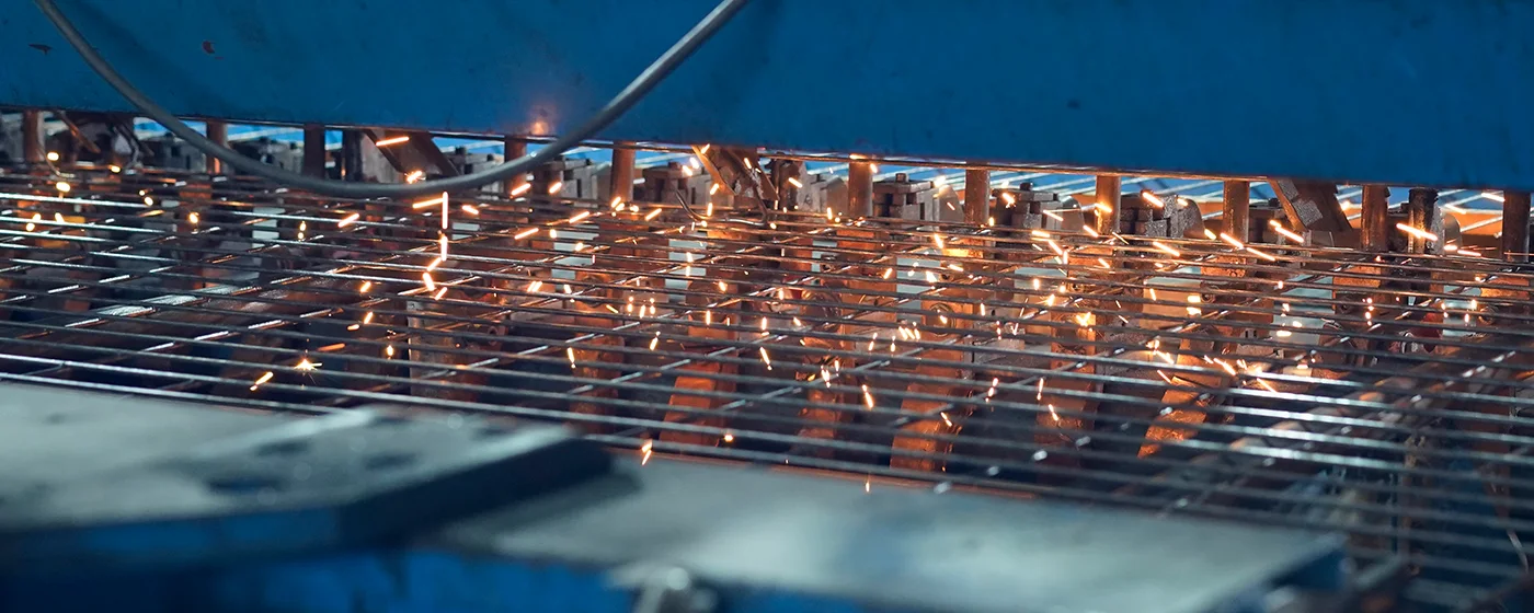  Two workers are welding the weld mesh onto frame of the fence gate.
