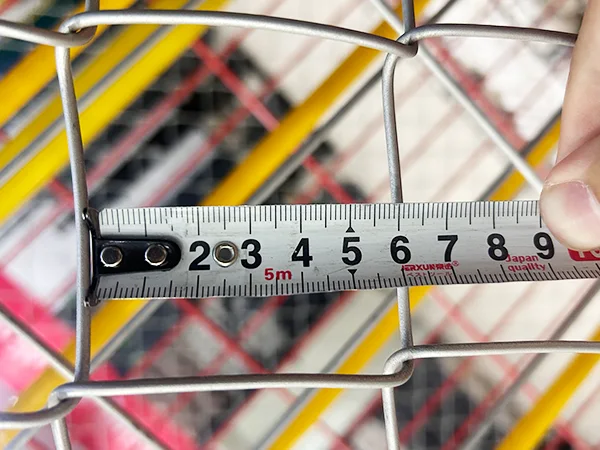 A QC worker is measuring the mesh size of Galvanized New Zealand temporary fence.