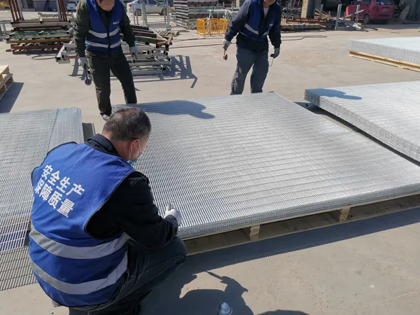 Workers are inspecting the quality of fences produced by Giant Fence outdoors.
