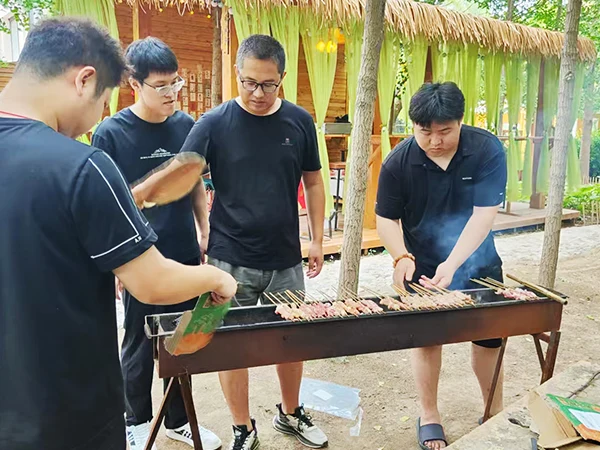 Four male sales representatives are barbecuing meat.