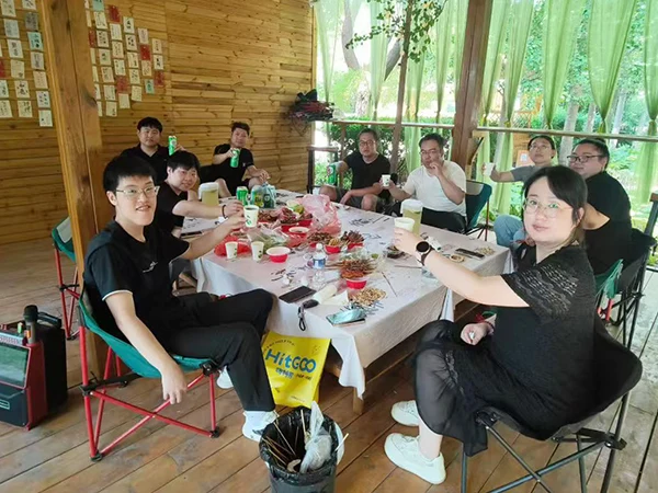 The team members are enjoying the barbecue and drinks.