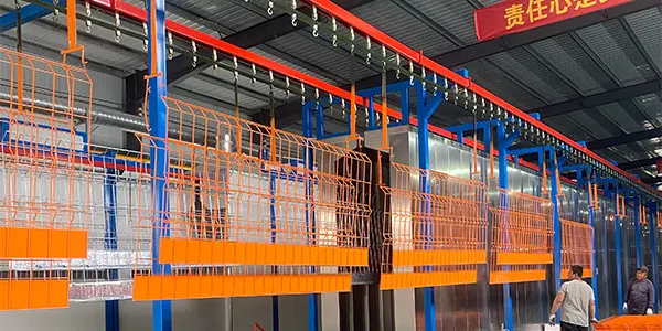 The orange edge protection fences are hanging on the powder coating line.
