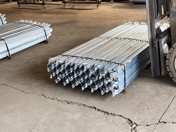 A forklift is carrying a metal pallet of palisade fence.