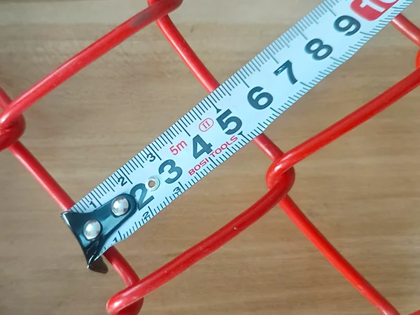 A QC worker is measuring the mesh size of PVC coated New Zealand temporary fence.