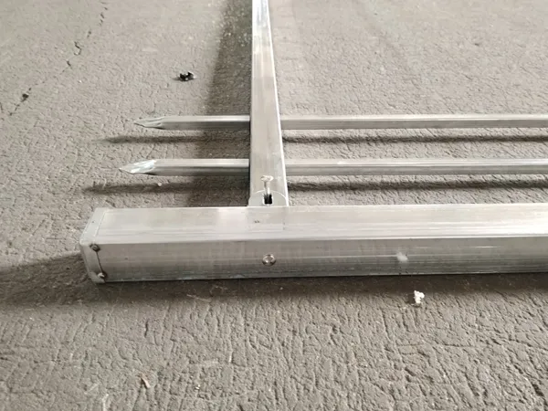 Close-up of galvanized steel tubular fencing post and pointed ground spikes
