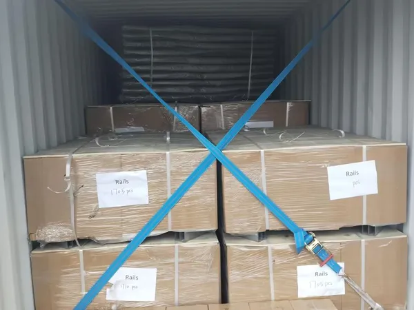 Container loaded with packed steel tubular fencing parts secured by tension straps
