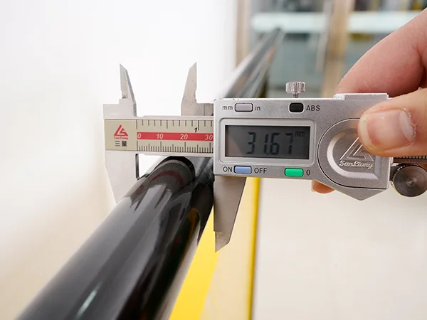 A QC worker is measuring the handrail size of all welded workshop safety fence.