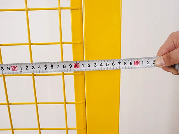 A QC worker is measuring the panel width of all welded workshop safety fence.
