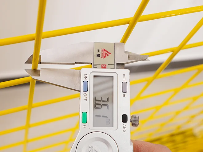 A QC worker is measuring the wire diameter of all welded workshop safety fence.